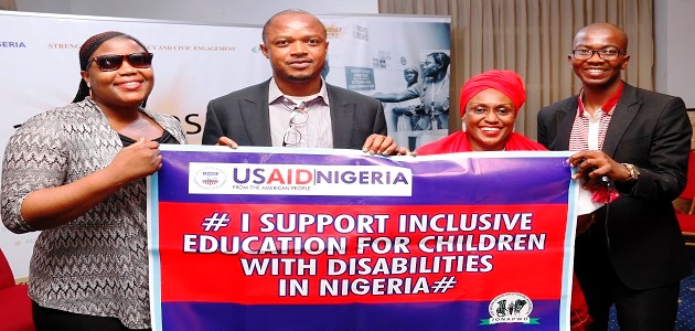 Four people hold up a banner saying, "I support inclusive education for children with disabilities in Nigeria."