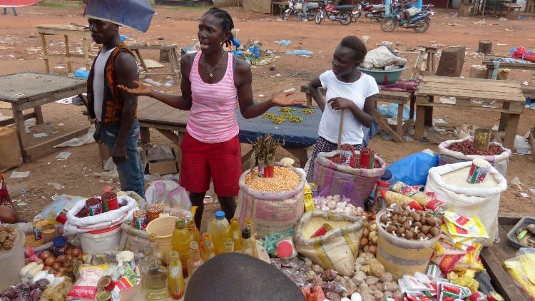 A woman and young girl stand by the food they are selling in a market