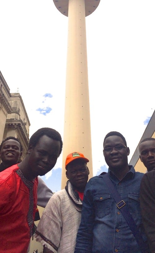 Five journalists pose in front of a tower
