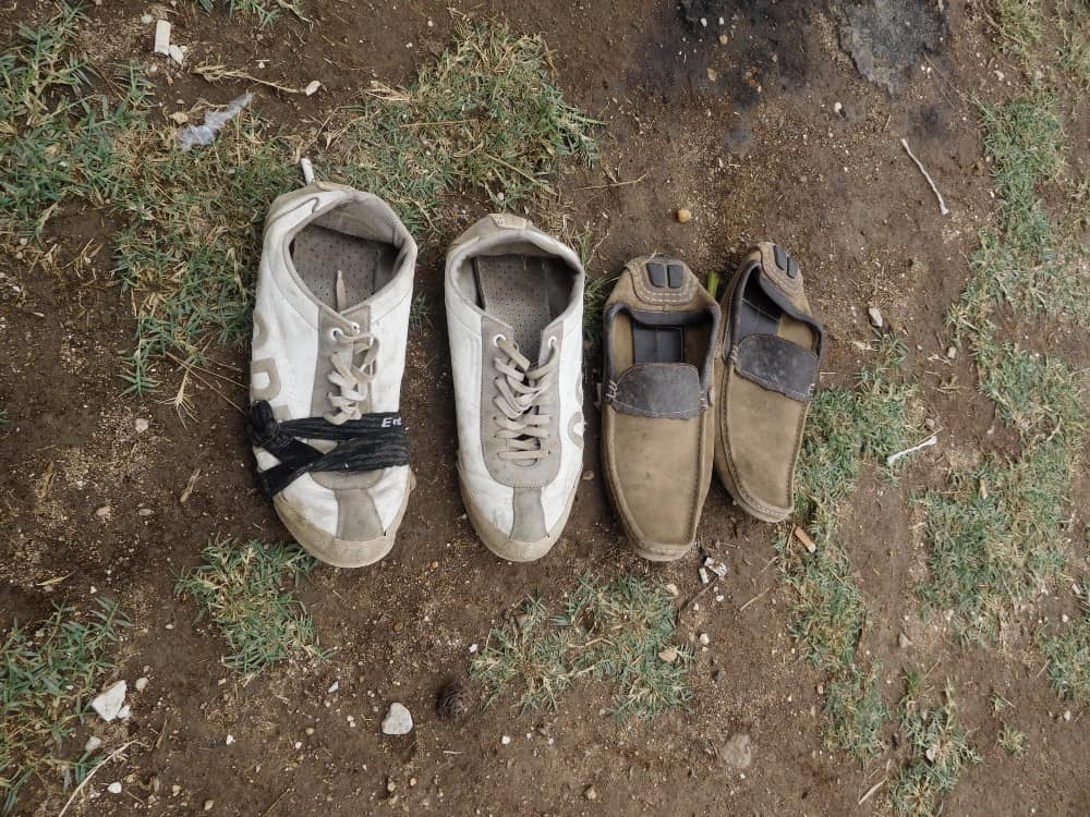 Two pairs of worn shoes are lined up on the ground