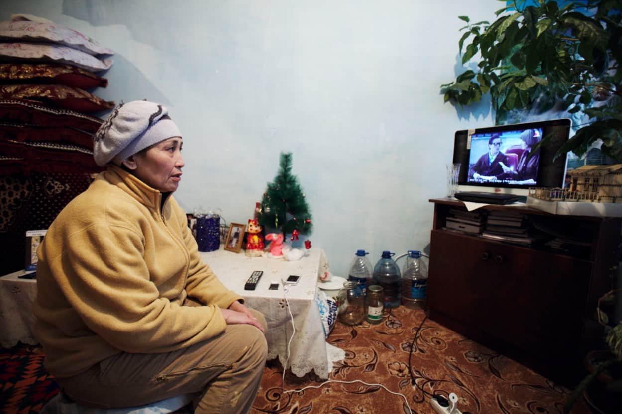 A woman sits in her living room watching TV.