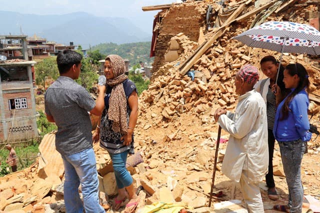 A journalist interviews a woman at a destroyed building