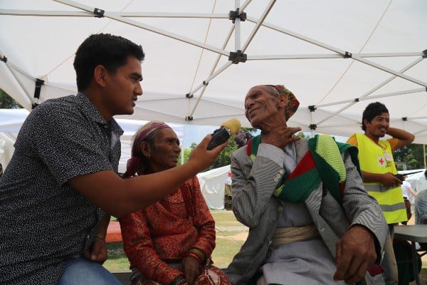 A reporter interviews an older Nepalese woman