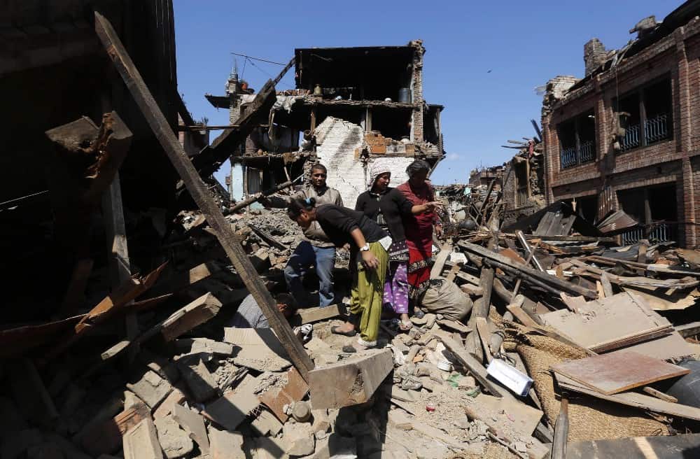 Four people in Nepal look at damage from the earthquake