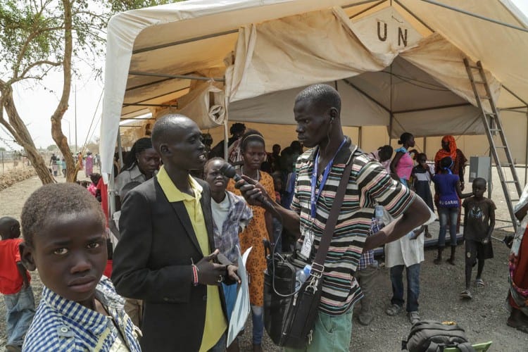 A journalist interviews a man outside a UN tent