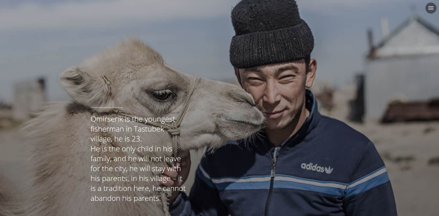 A young man stands next to a camel