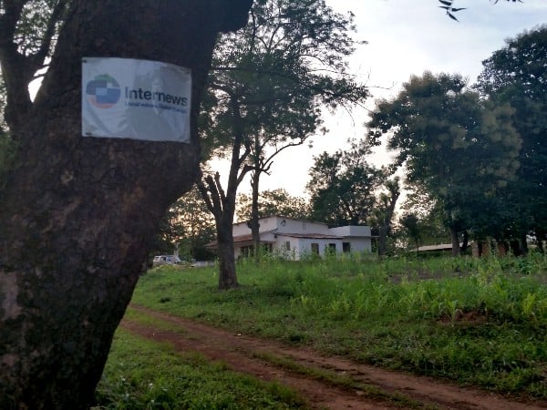 An Internews sign is tacked to a tree