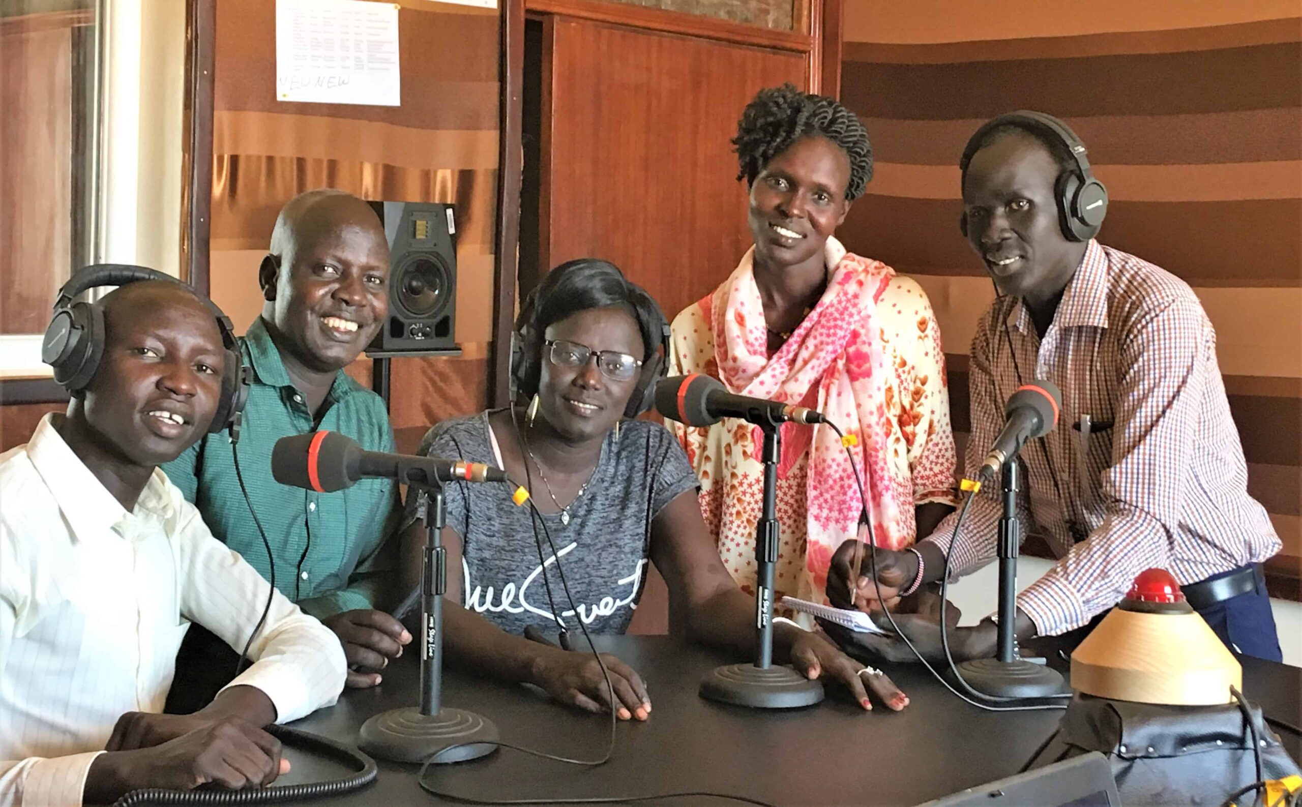3 men and 2 women sit at a table in the Aweil radio studio.