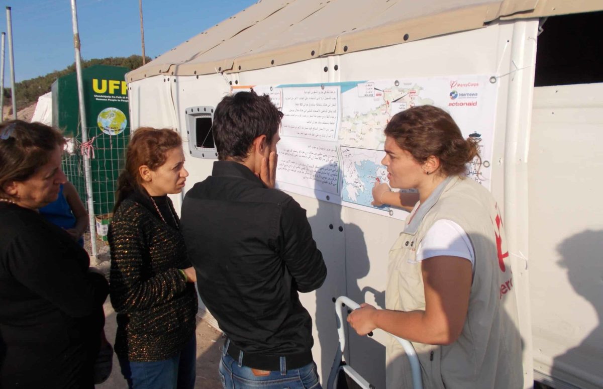 A woman points to a large map posted on the side of a tent