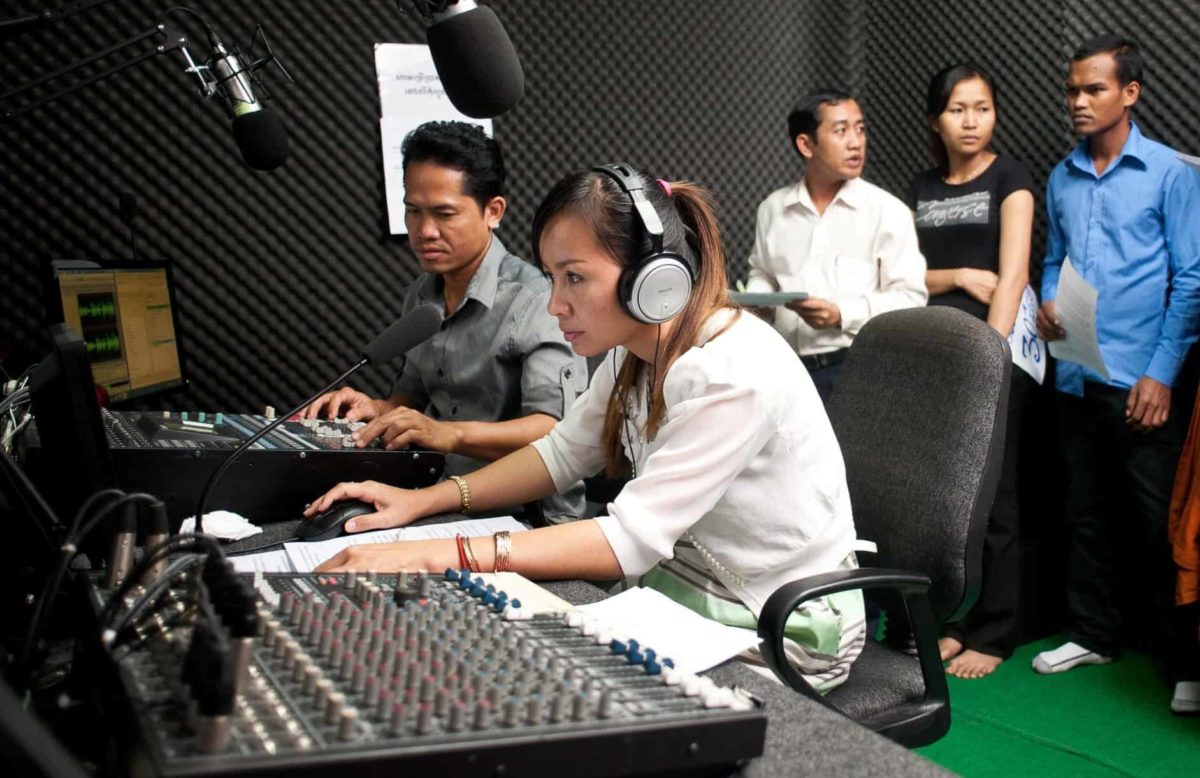 A group of people gather in a radio studio