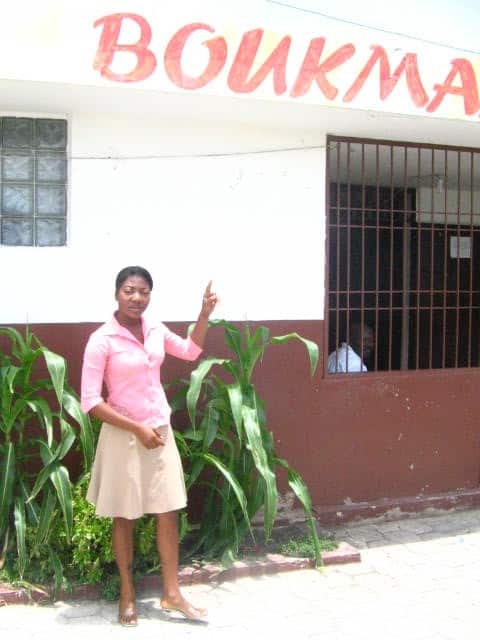 Fabienne pointing to a sign out front of the radio station where she works