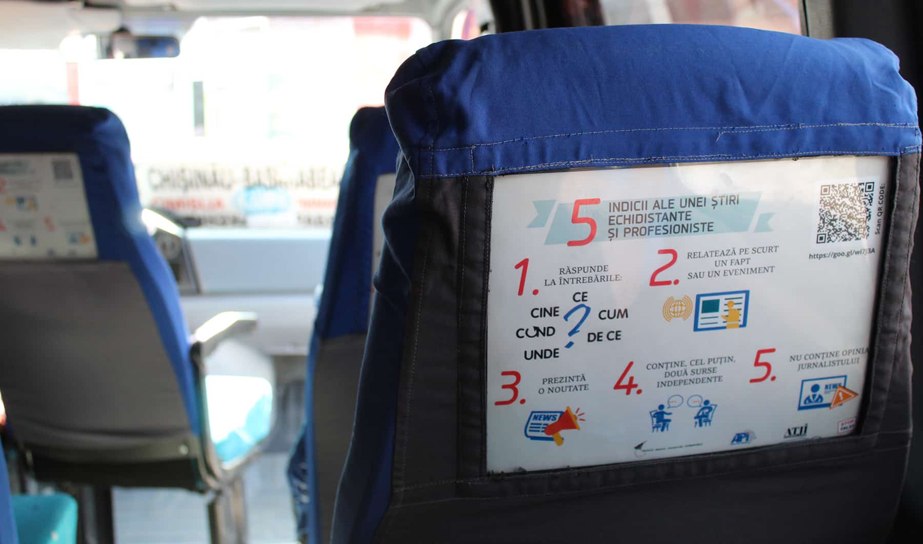 A poster is applied to the back of a seat in a mini bus