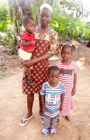 Woman stands holding a baby with 2 children by her site