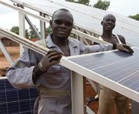 Two men stand by a solar panel installation