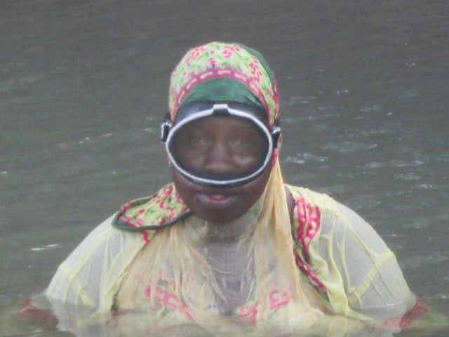 A woman with diving gear on stands in the water