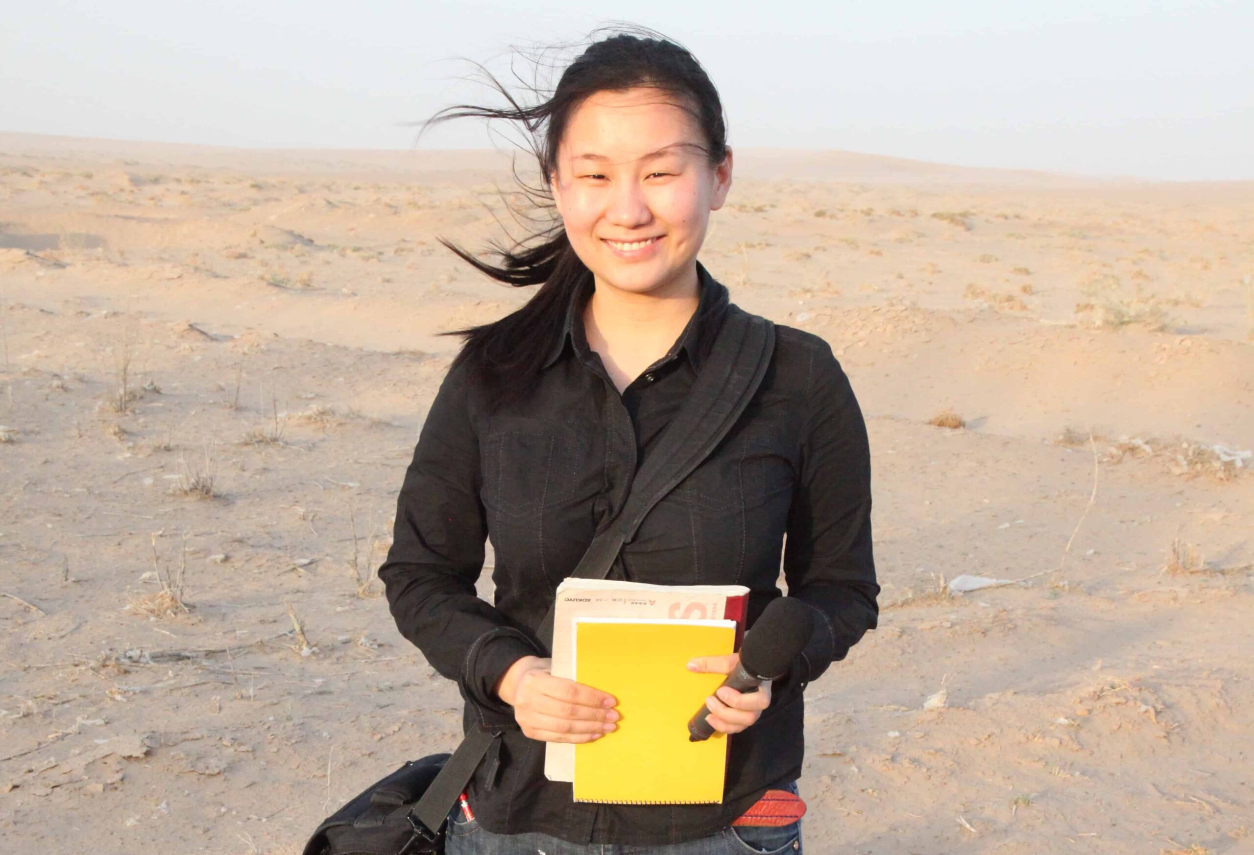 Cui Zheng stands in the desert holding a notebook