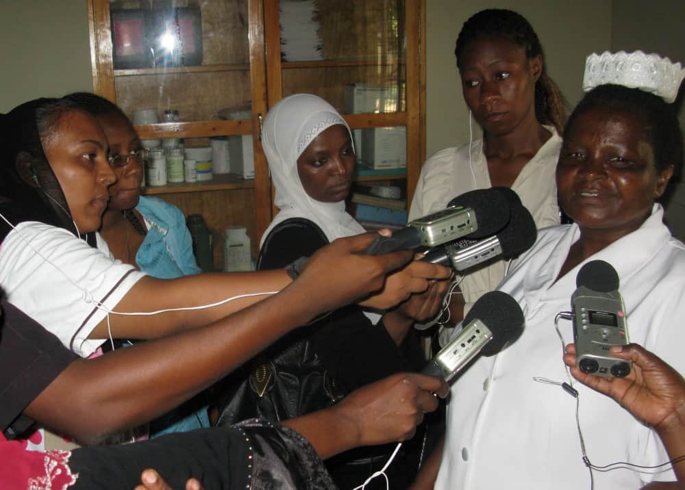 Several women journalists interview a woman health worker