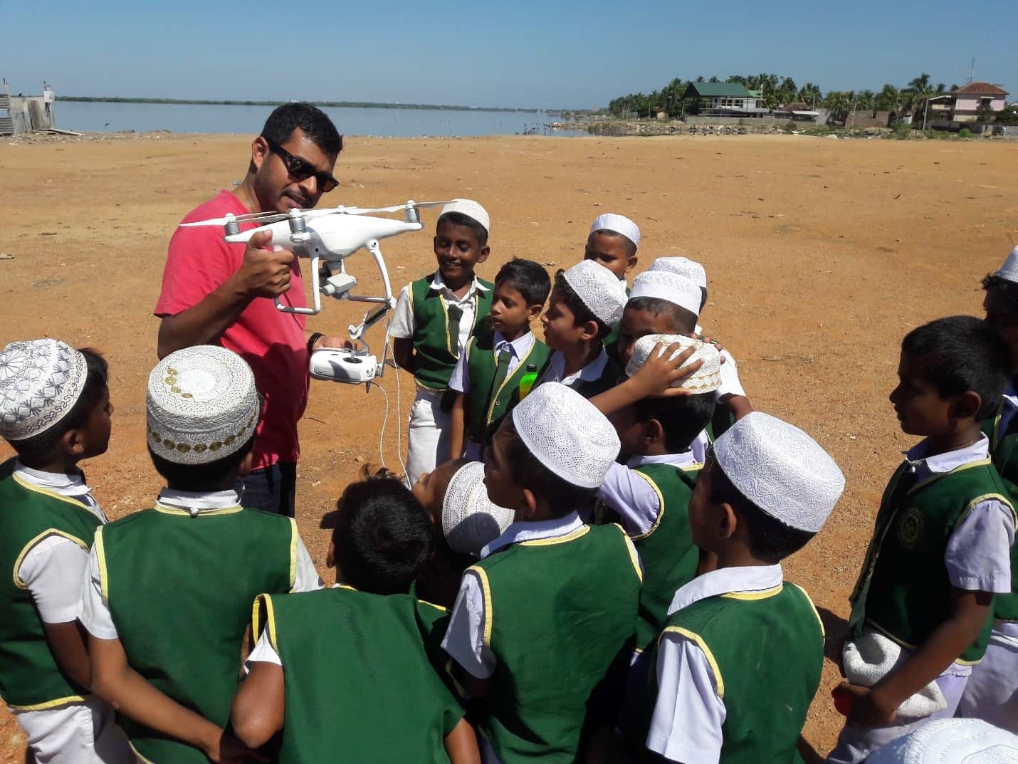 A man shows a group of school boys a drone