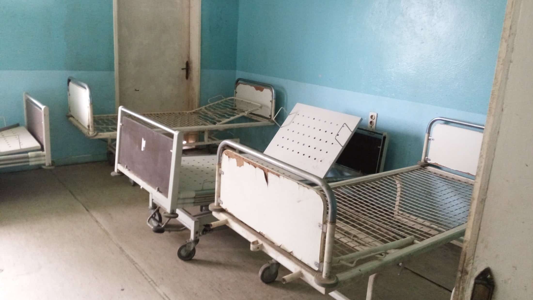 Empty metal beds in a hospital room.