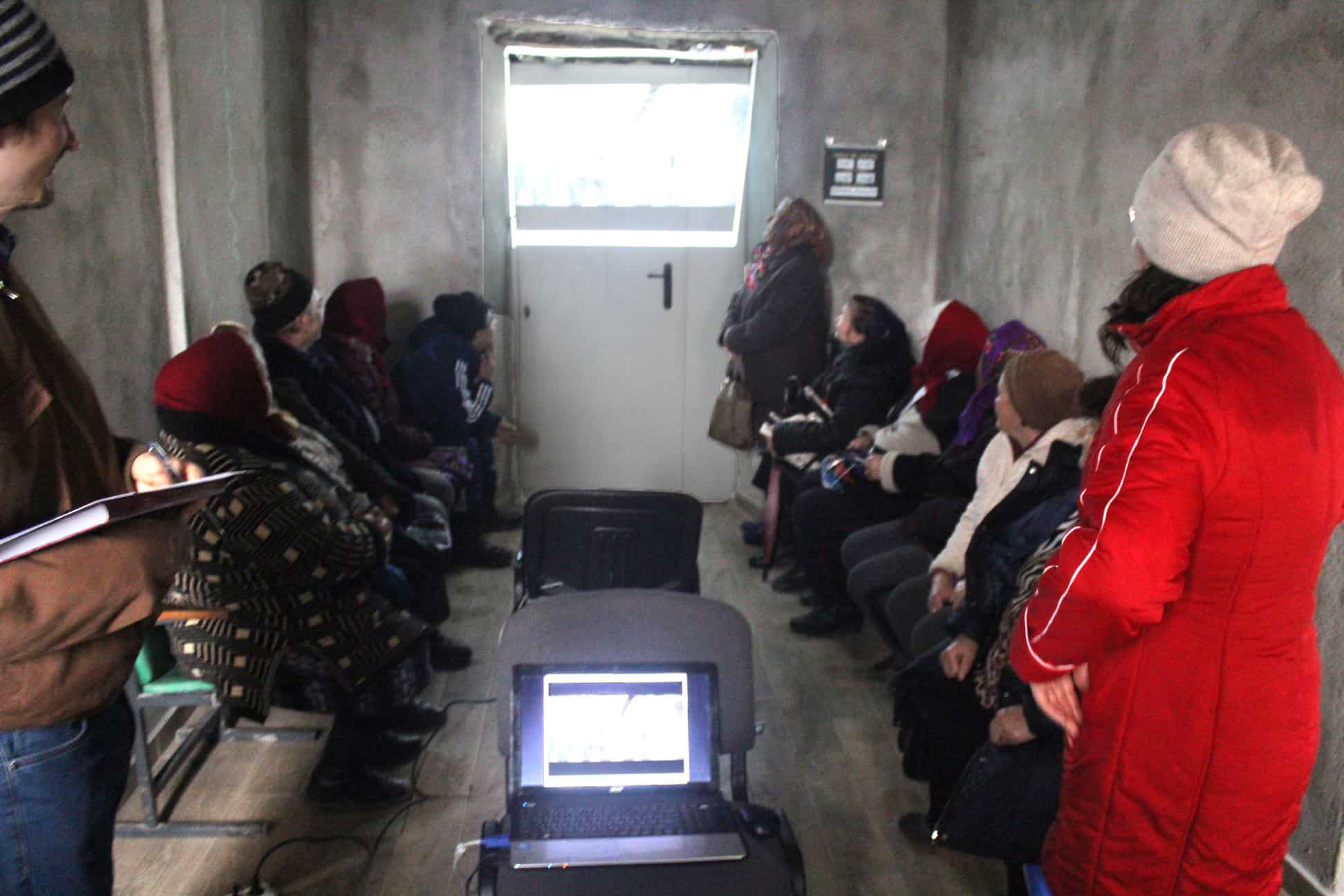 A group of older people sit watching a video