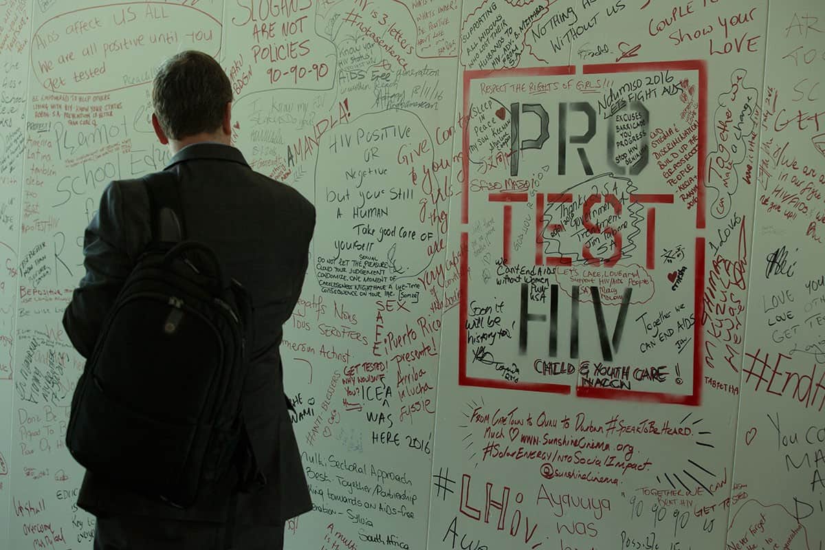 A man looks at a whiteboard with HIV messages on it