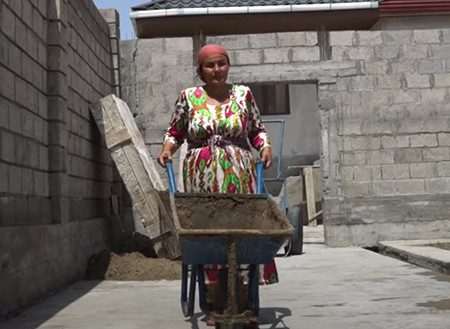 A woman pushes a wheelbarrow