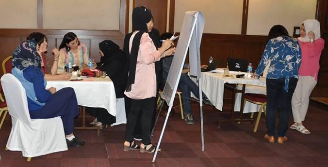 A group of women work on an easel in a room