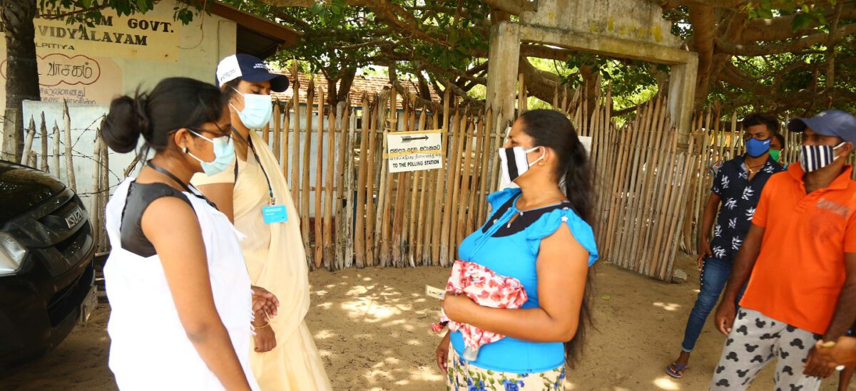 People stand outside wearing face masks, talking