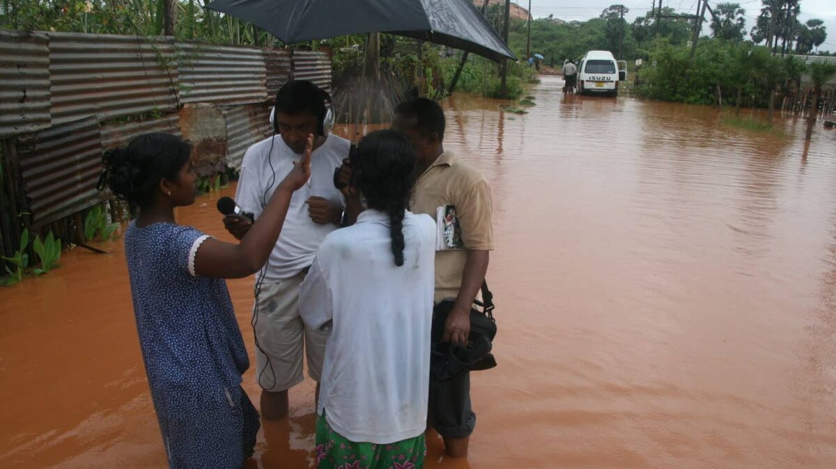 A group of people stand in deep water on a flooded street