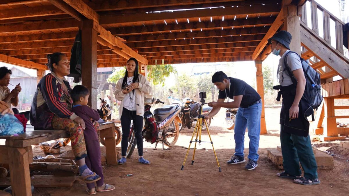 Some young people film a woman and a child under a deck