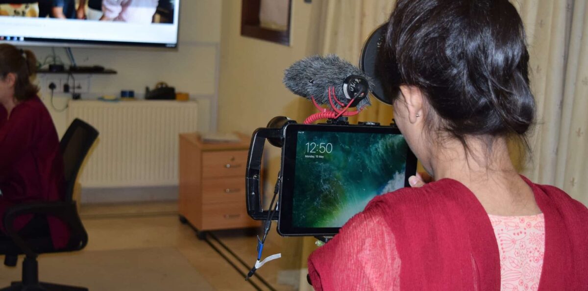 A woman looks through the lens of a video camera.