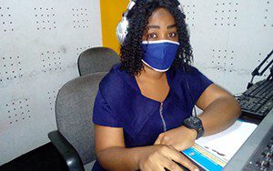 A woman wearing a face mask works on a laptop computer.