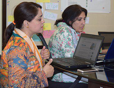 Two women sit at laptop computers.