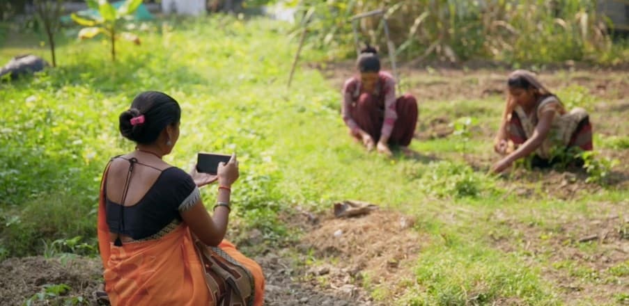 A woman films two women farmers.