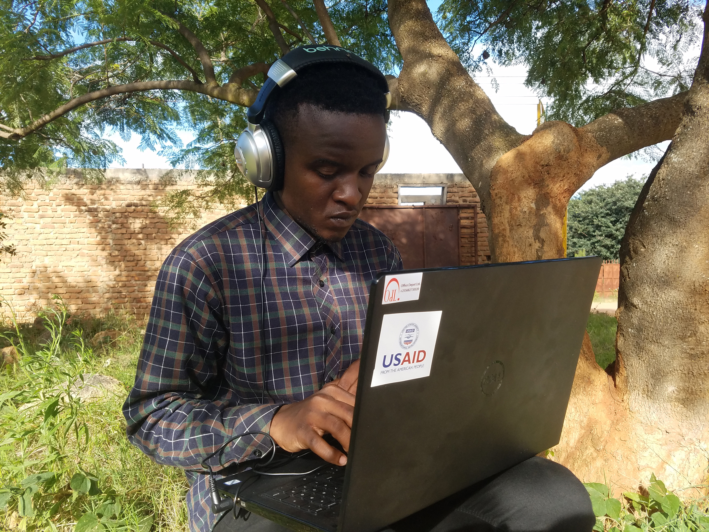 A man wearing headphones works on a laptop computer