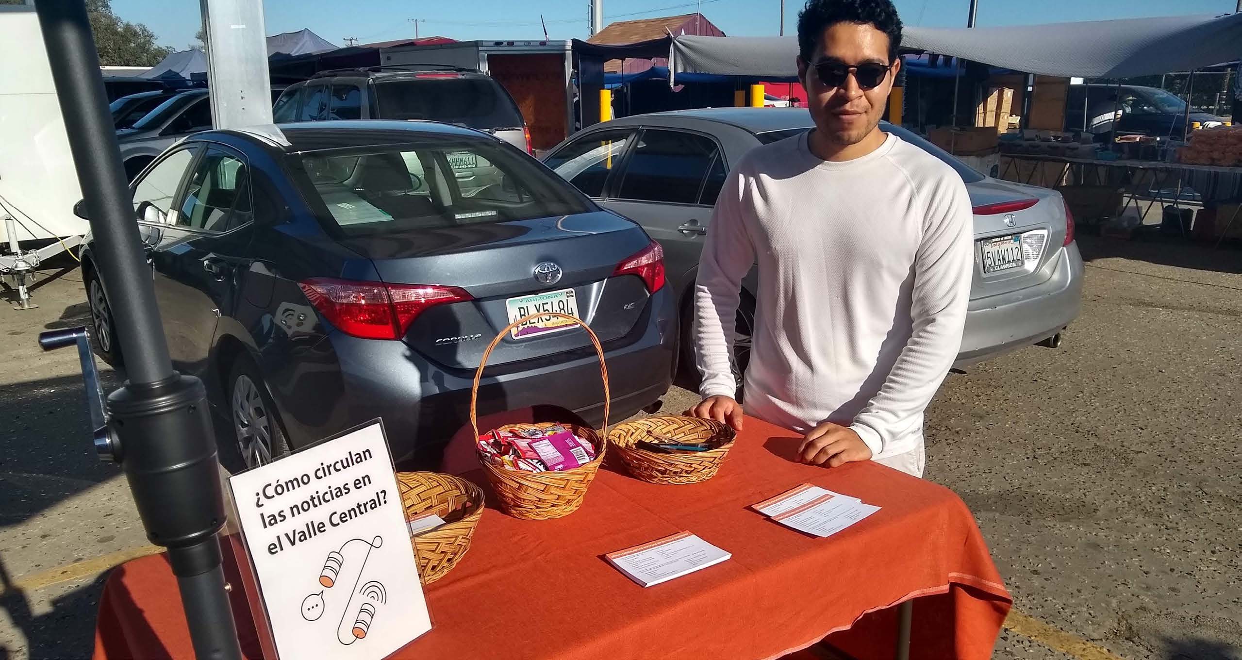 A man stands outside behind a table with pamphlets on it.