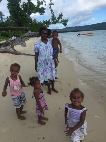 A woman stands with 4 children on the beach