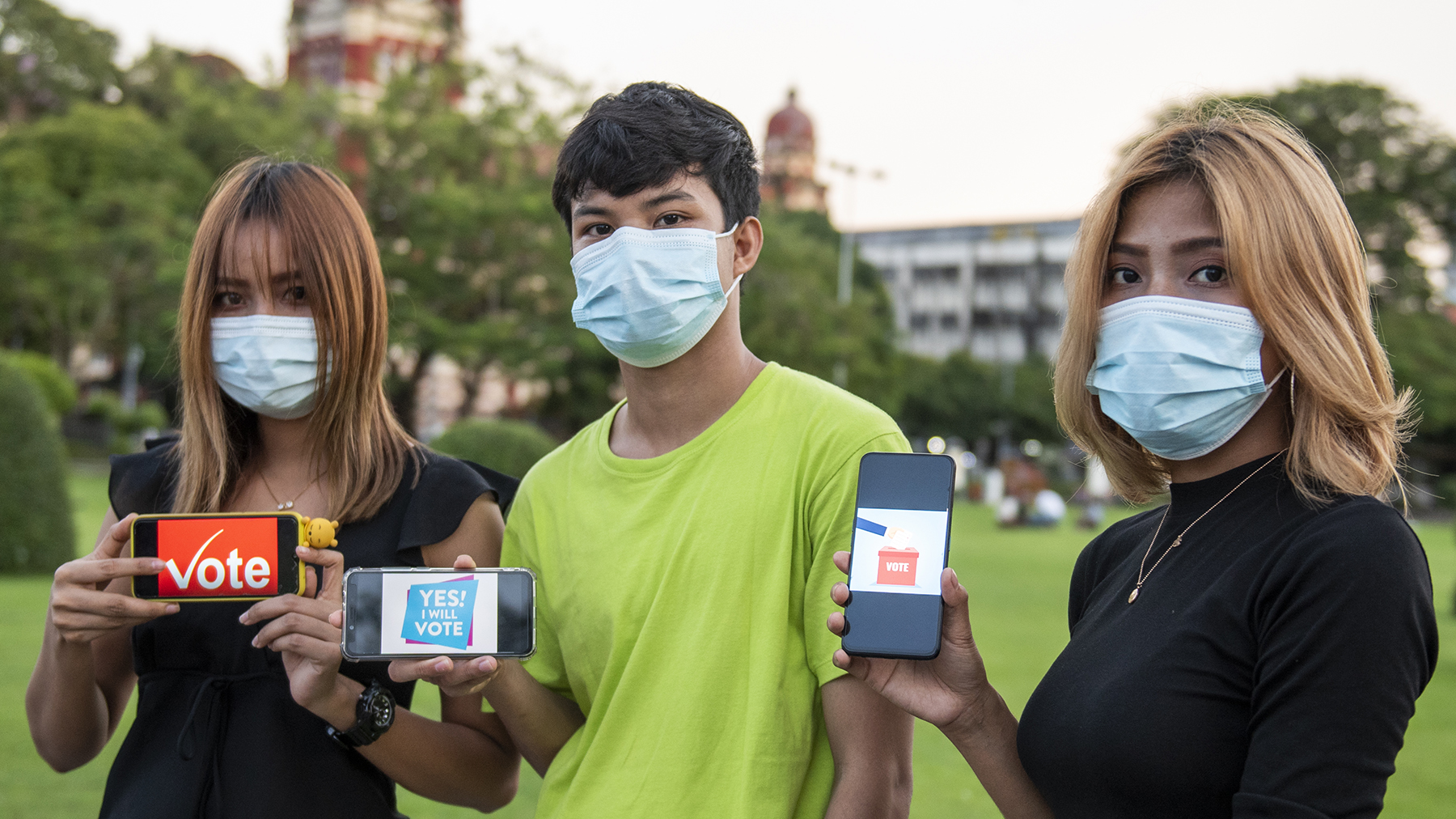 3 young people wearing masks hold up phones that say 