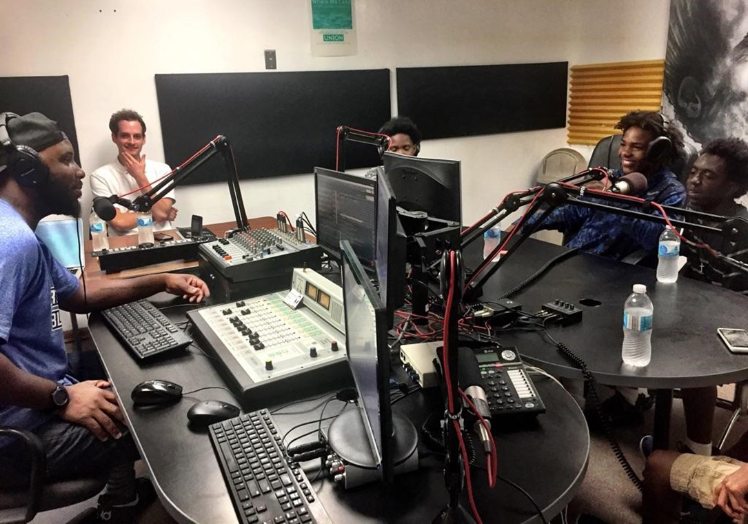 5 young men sit in a radio studio