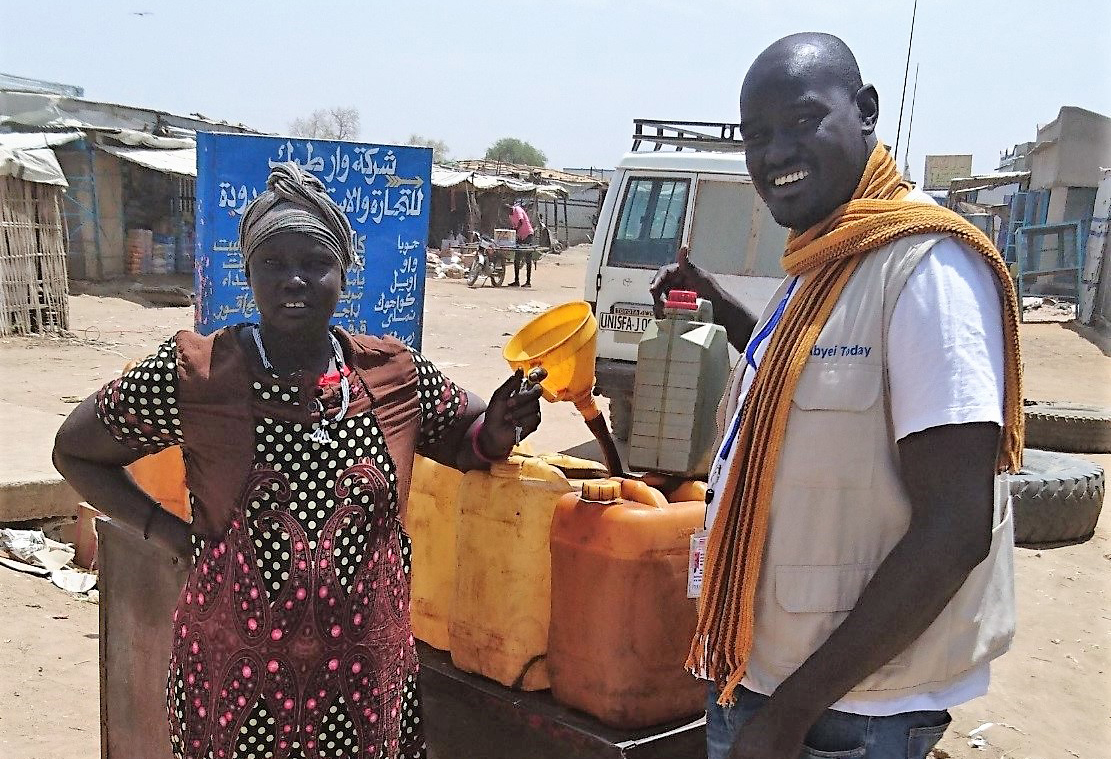 A woman and a man stand next to a fuel tank