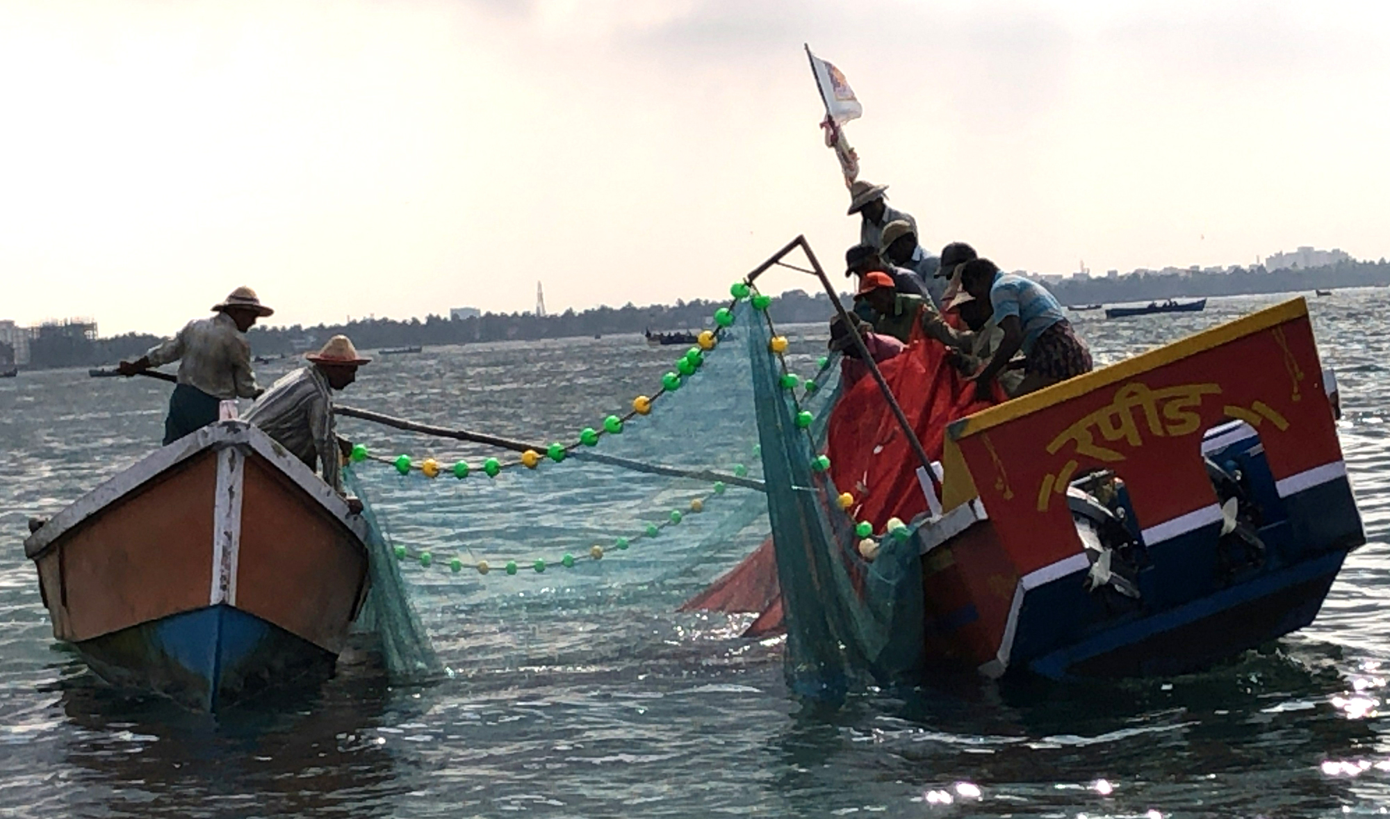 Two small boats are next to each other in the water, connected by ropes
