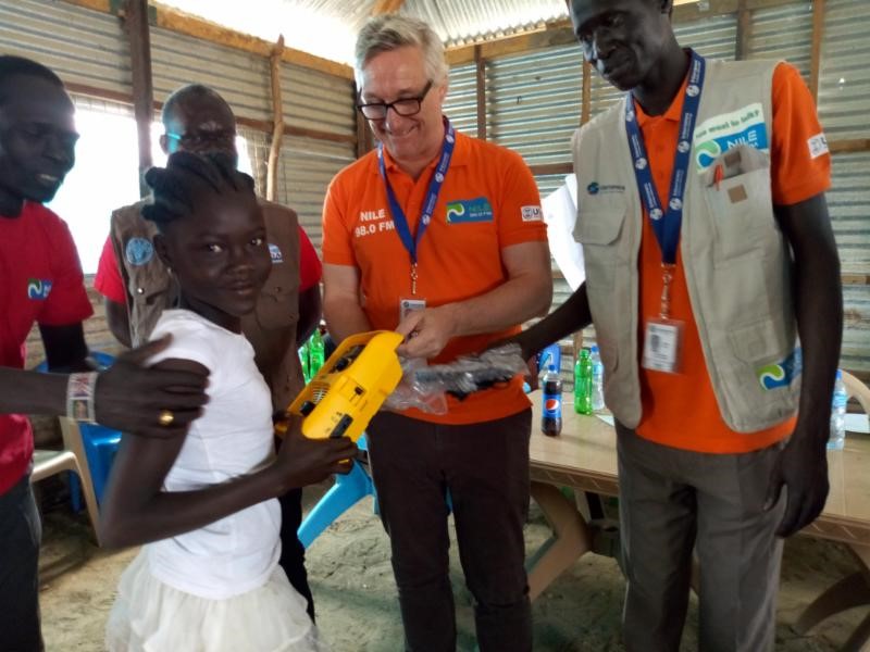 A man hands a radio to a young girl