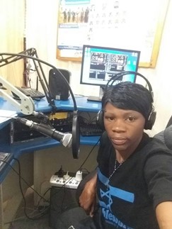 A woman sits in front of a mic in a radio studio