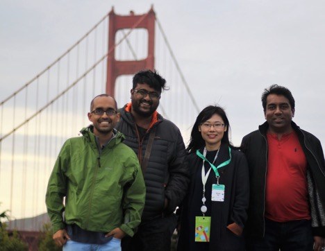 3 men and a woman pose with the Golden Gate Bridge behind them
