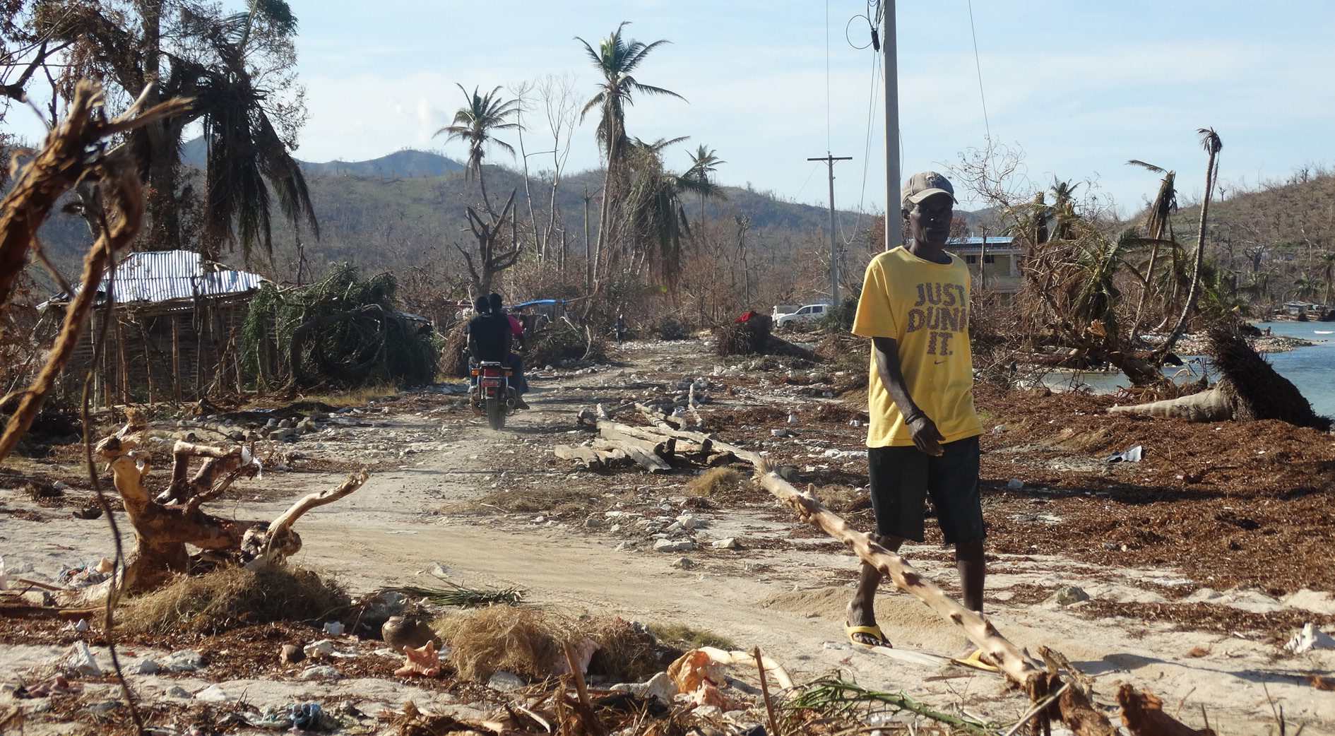 A man walks down a path in the midst of hurricane destruction