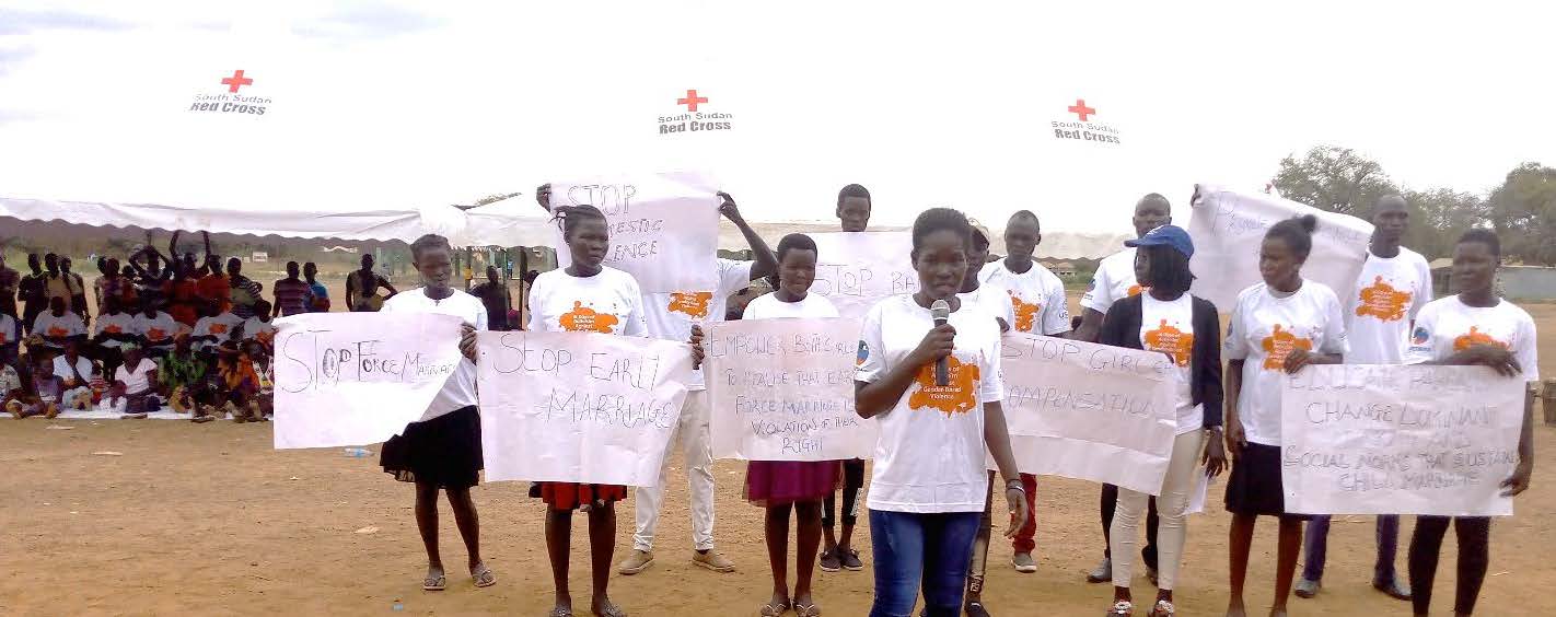 A group of girls stand holding posters that say "Stop early marriage"