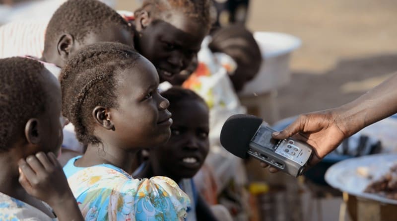 A group of children speak into a mic.