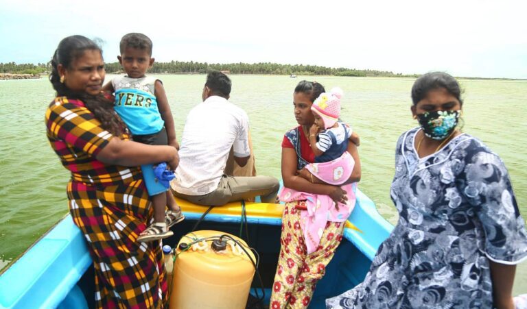 A man and three women on a small boat; two women are holding children.