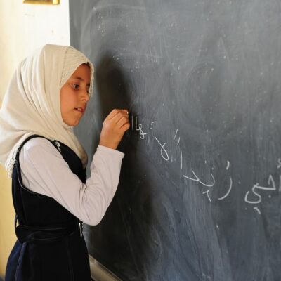 A girl writes on a blackboard.