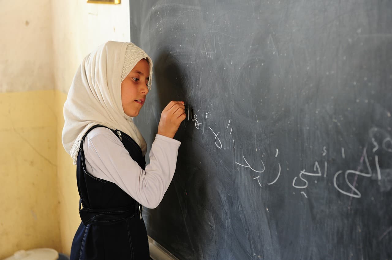 A girl writes on a blackboard.